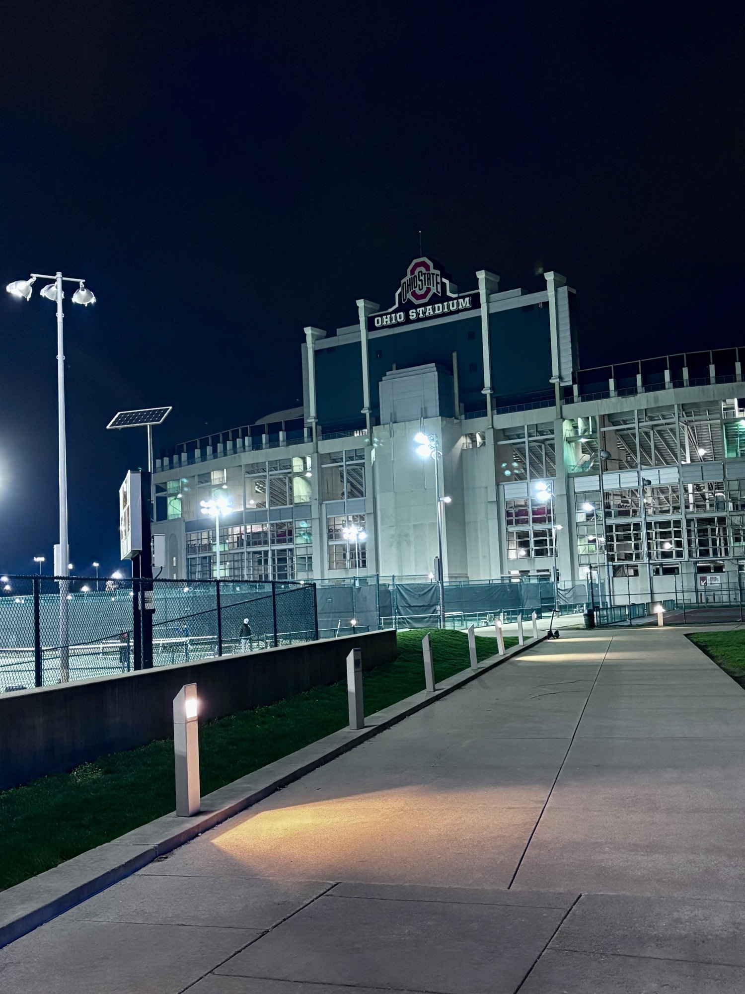 Ohio Stadium lit at night with an empty walkway leading to the gates